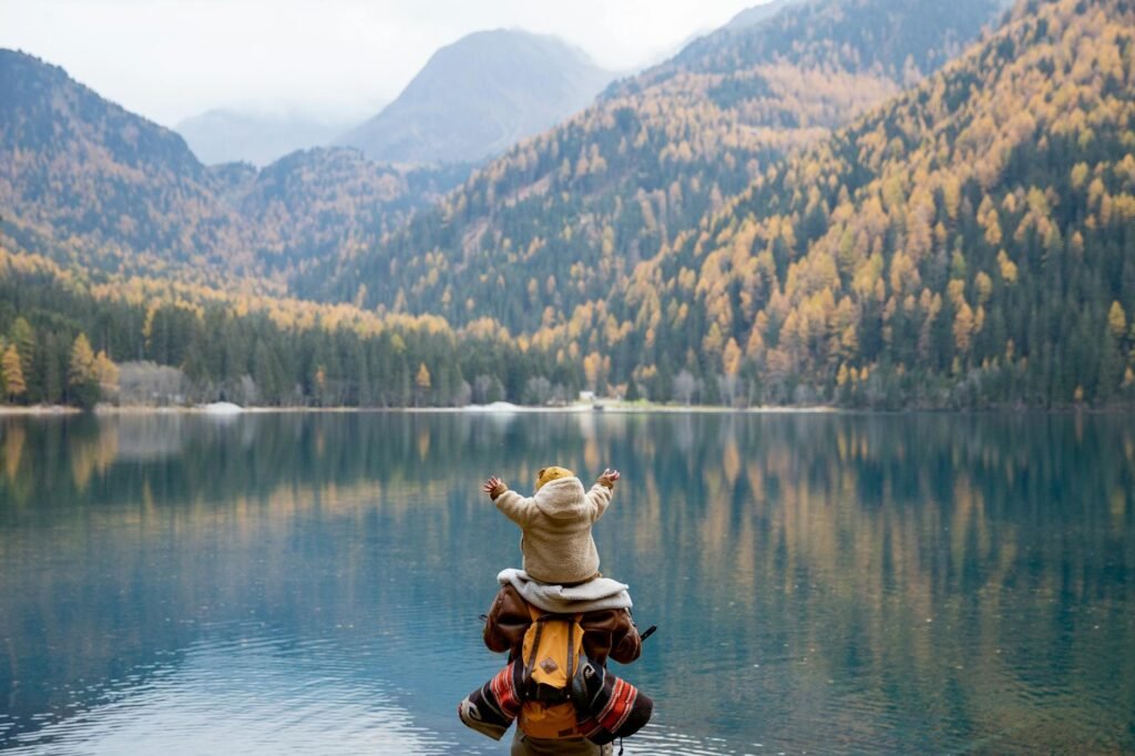 back view of a person carrying a baby near the placid lake scenery