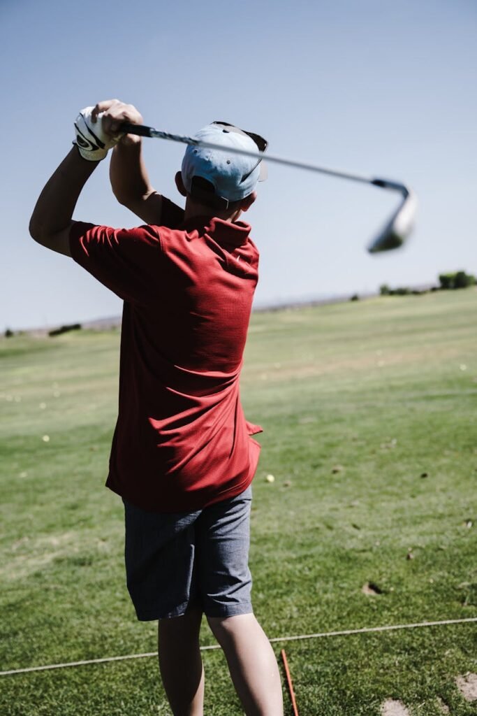 man swinging golf club facing grass field - quel budget pour jouer au golf 