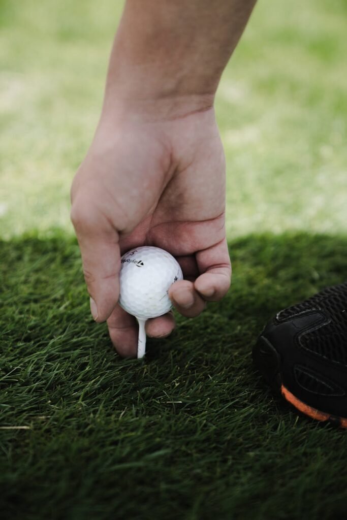 person holding golf ball - quel budget pour jouer au golf 