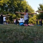 women performing yoga on green grass near trees