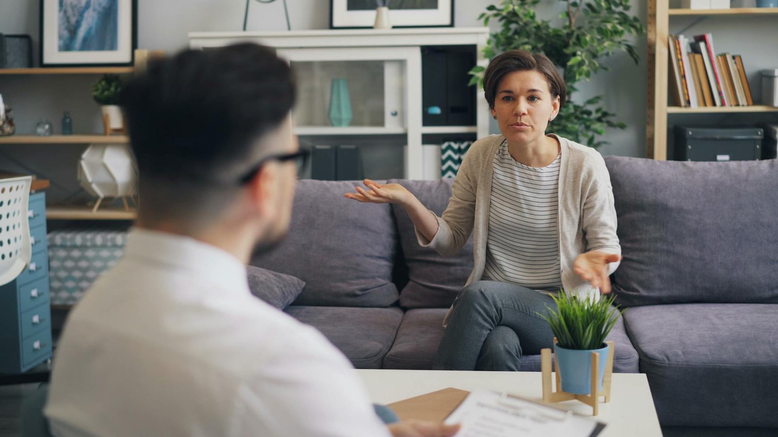 a woman and man sitting on a couch talking